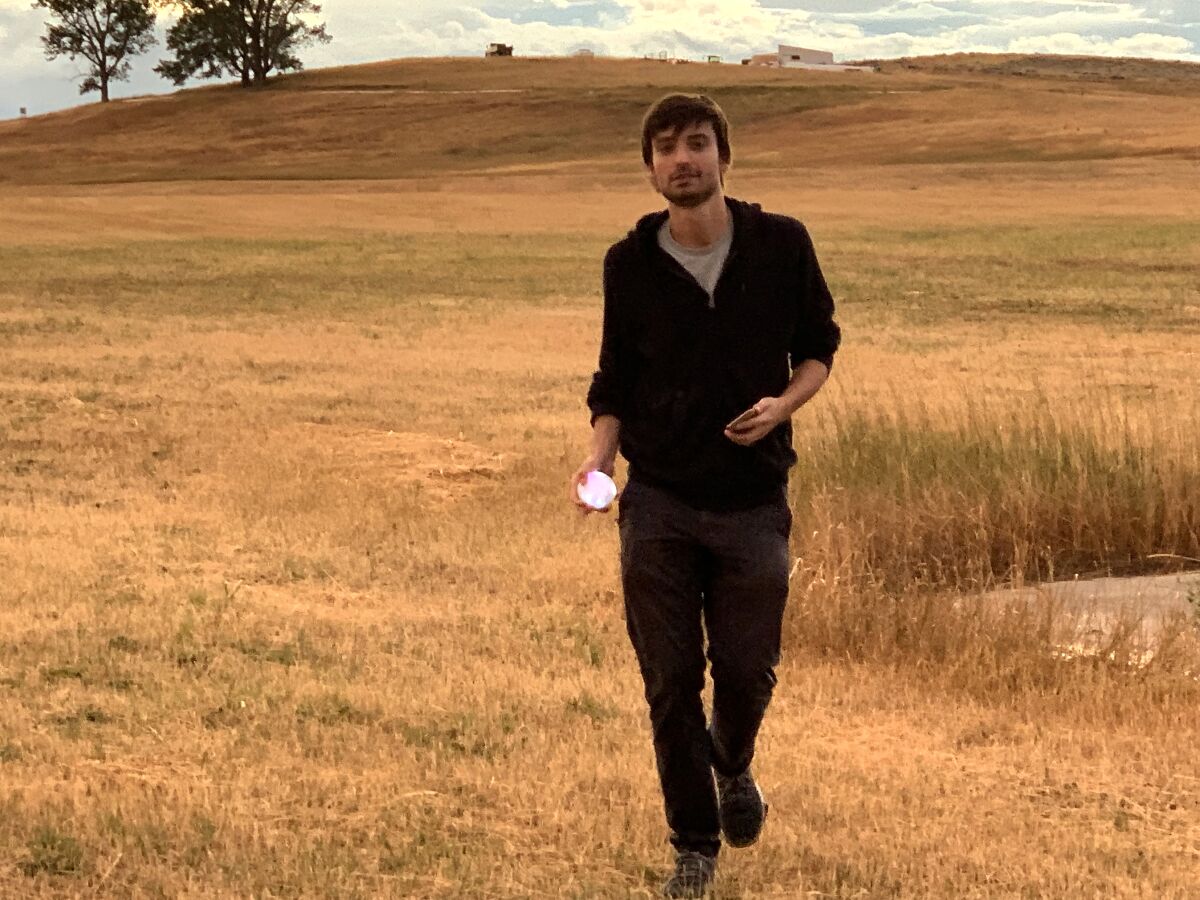 A man dressed in black walks in a field