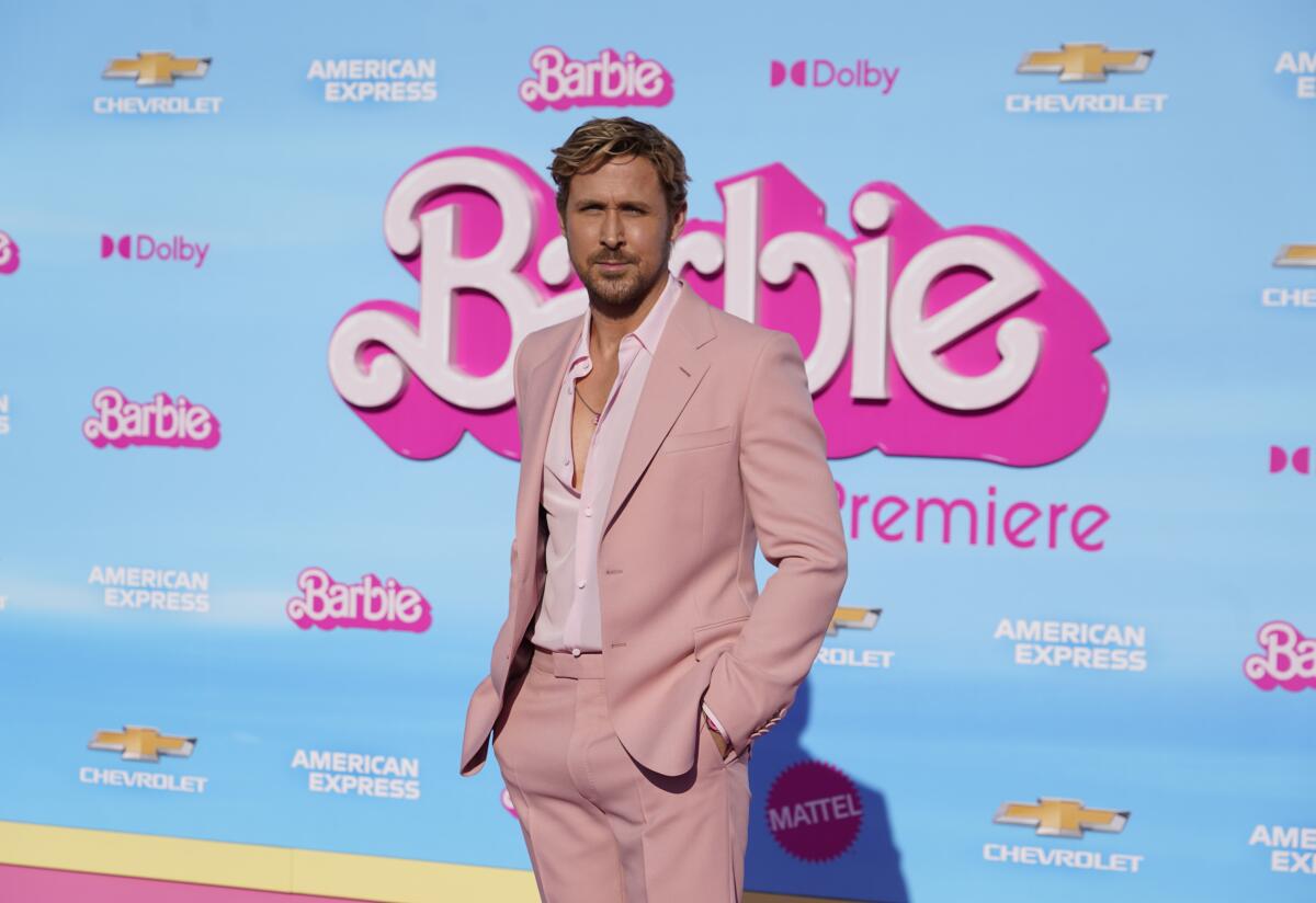Ryan Gosling squints in the sunlight while posing a pale pink suit at a movie premiere