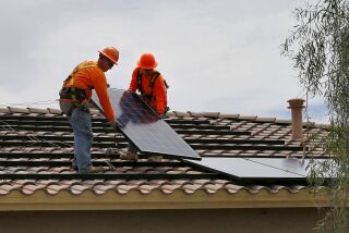 In this July 28, 2015, photo, electricians Adam Hall, right, and Steven Gabert, install solar panels on a roof for Arizona Public Service company in Goodyear, Ariz. Traditional power companies are getting into small-scale solar energy and competing for space. The emerging competition comes as utilities and smaller solar installers fight over the future of the U.S. energy system. (AP Photo/Matt York)