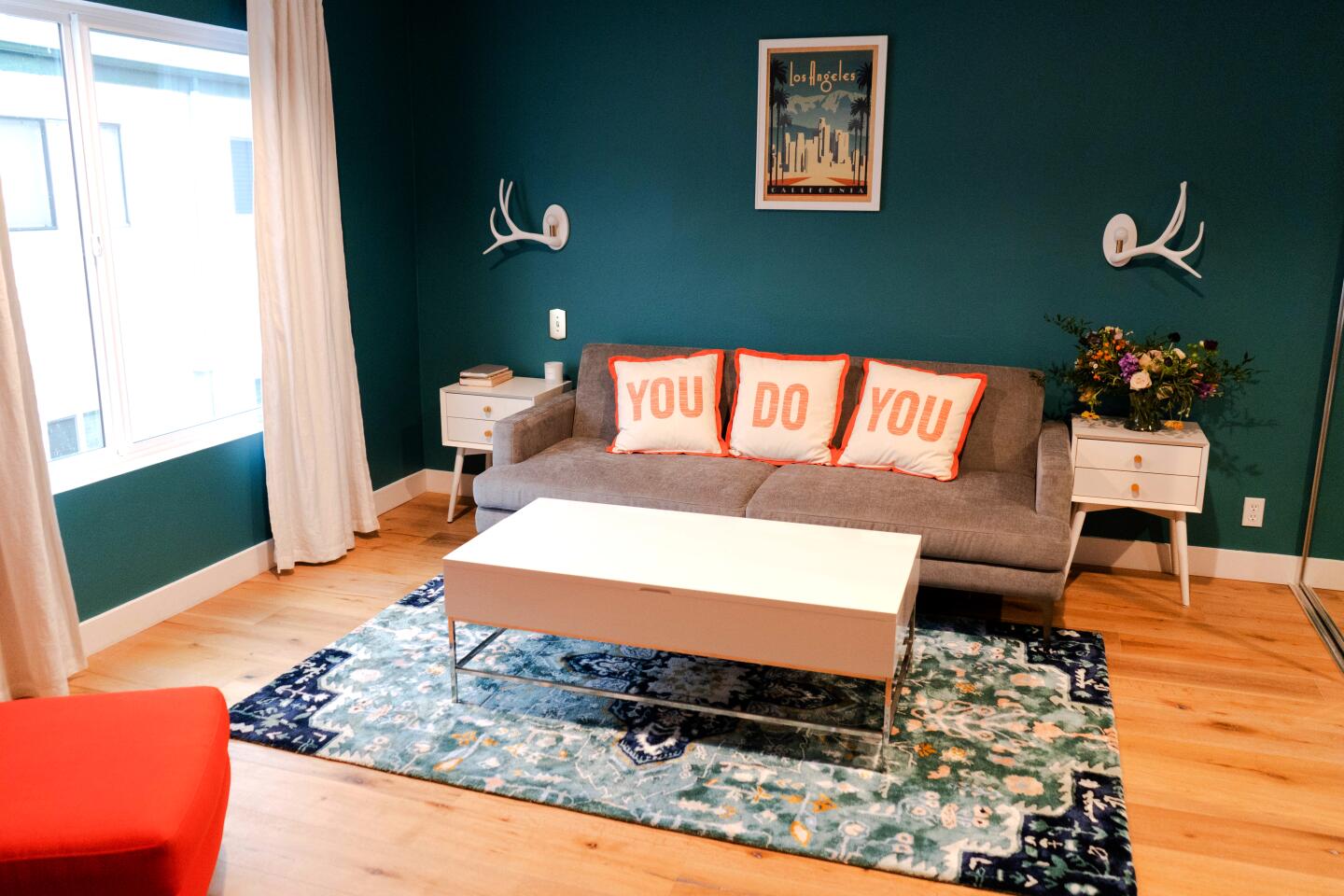 Actress Sarayu Blue painted the walls of her favorite room a deep turquoise and laid down a floral teal rug from Anthropologie. A trio of couch cushions from the set of her 2018 NBC sitcom "I Feel Bad" spell out “You Do You.”