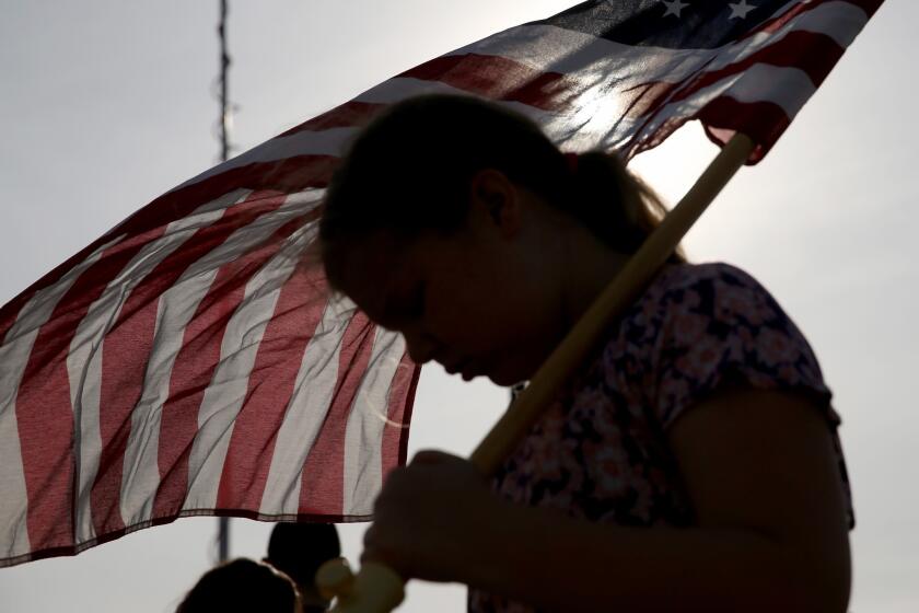 Jenna Ryan, 11, holds a flag as she participated Friday in a flag walk in memory of those killed and injured on the Ft. Hood Army post this week.