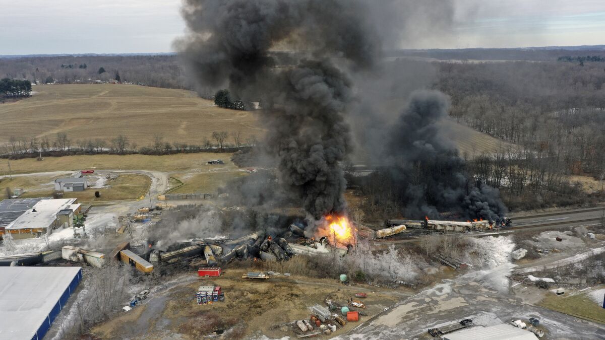 Flames and black smoke rise from derailed freight train cars