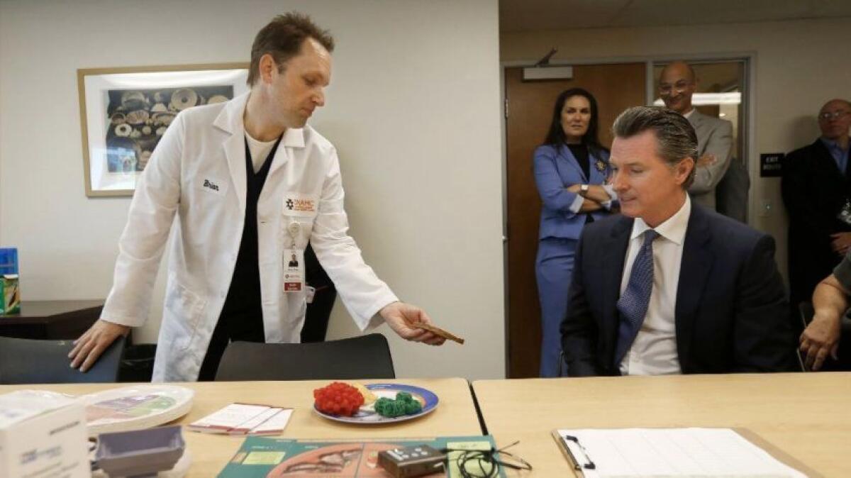 El gobernador Gavin Newsom, a la derecha, se reúne con el coordinador del programa de diabetes, Brian Shaw, durante una visita el 9 de julio al Sacramento Native American Health Center. (Rich Pedroncelli / Associated Press)