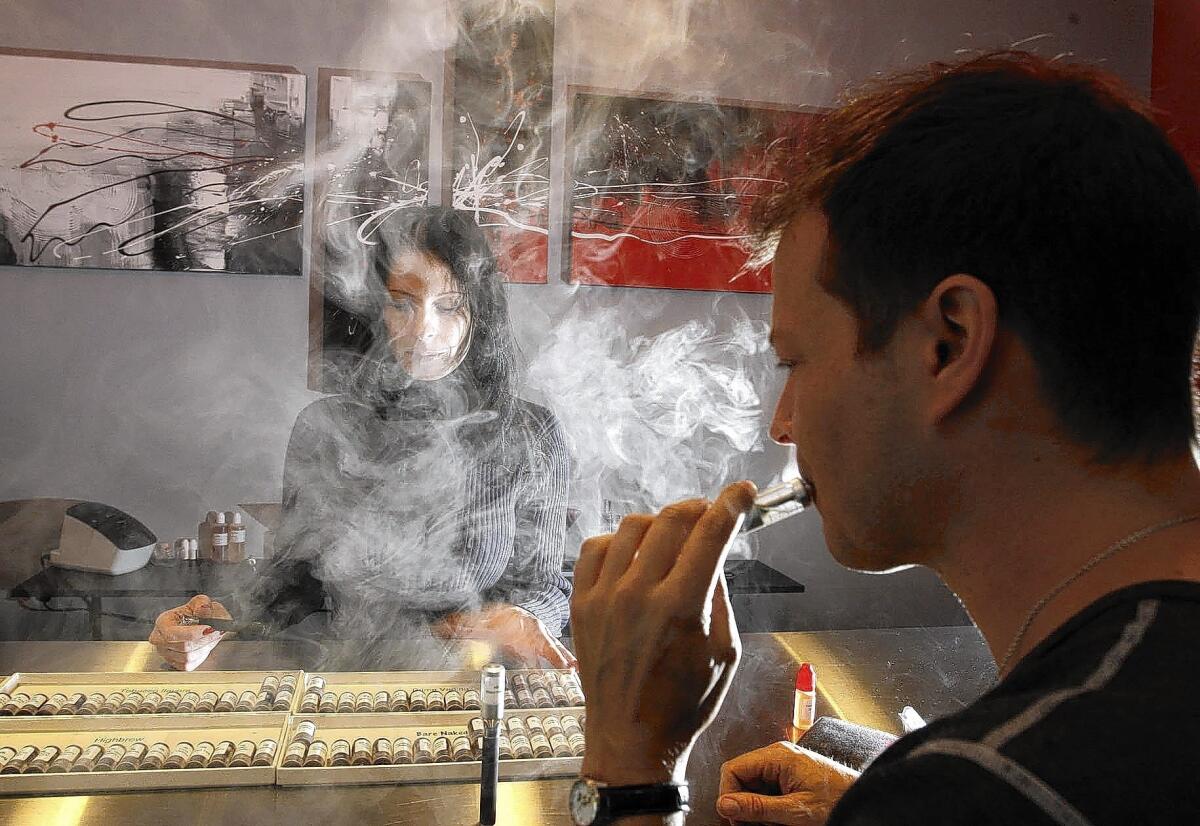 Jason Wingo, 42, tries an e-cigarette at Natural Vapes in West L.A. Assisting him is co-owner Elaine Ruggieri, who said the proposed ordinance would set back the efforts of some smokers to kick the tobacco habit. Wingo was a pack-a-day smoker for 10 years who says vaping helped him quit.