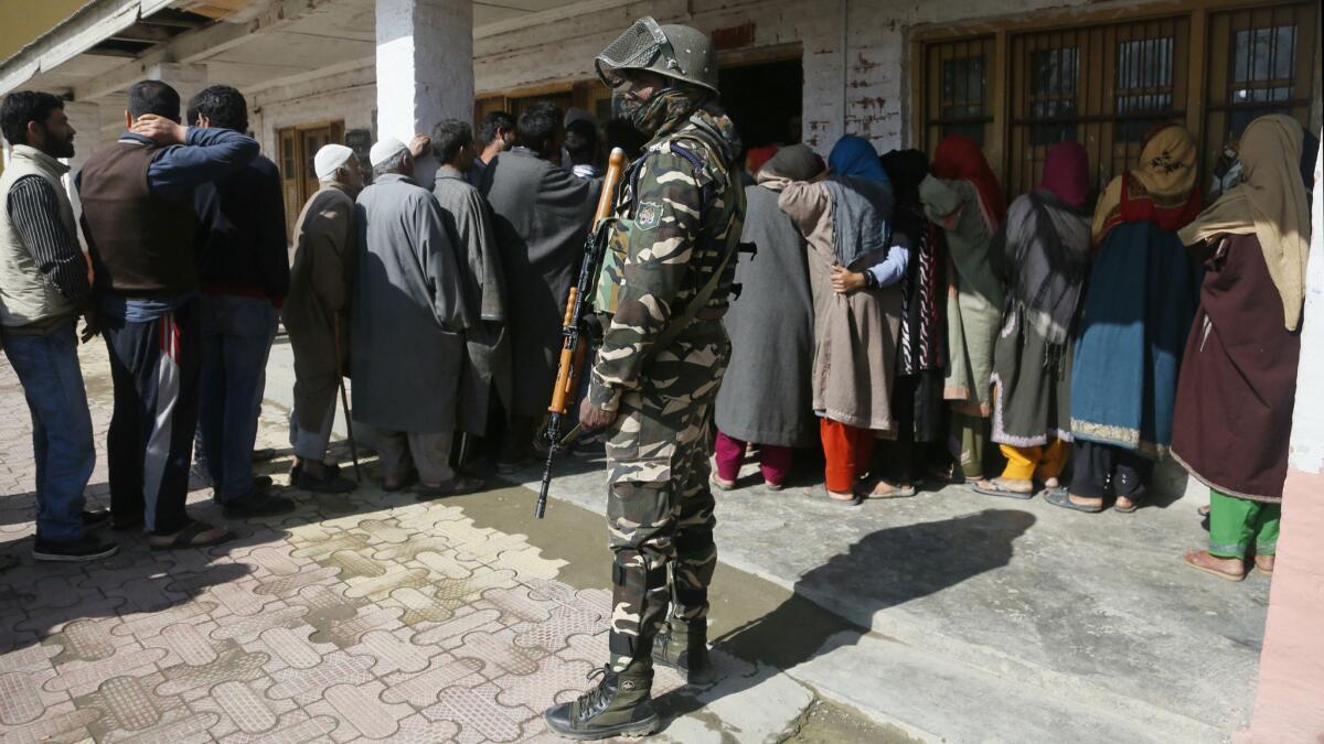 An Indian paramilitary soldier stands guard as Kashmiri voters wait in a queue to cast their votes outside a polling station during the second phase of India’s general elections, on the outskirts of Srinagar, Indian-controlled Kashmir, on Thursday.