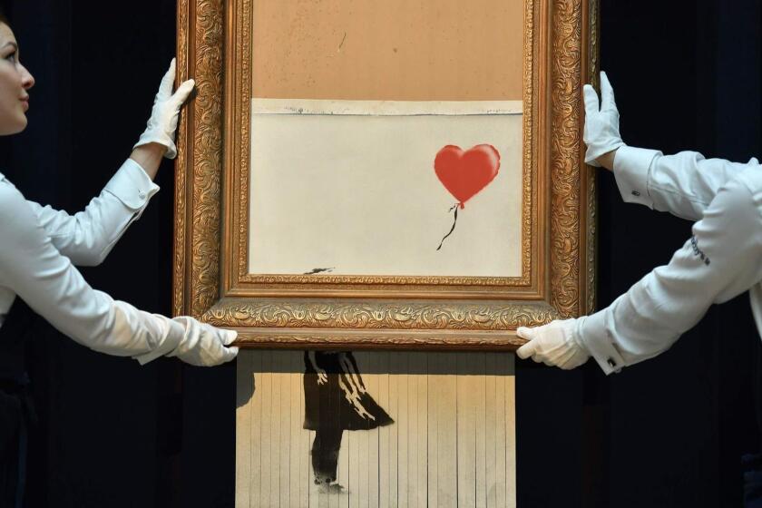 -- AFP PICTURES OF THE YEAR 2018 -- Sotheby's employees pose with the newly completed work by artist Banksy entitled "Love is in the Bin", a work that was created when the painting "Girl with Balloon" was passed through a shredder in a surprise intervention by the artist, at Sotheby's auction house in London on October 12, 2018, following the work's sale. - The buyer of a work by street artist Banksy that was partially destroyed moments after it sold has gone through with the purchase, Sotheby's auction house said on October 11, 2018. The painting "Girl with Balloon" was passed through a shredder hidden in the frame just after it went under the hammer last week for £1,042,000 ($1.4 million, 1.2 million euros). The modified version has now been certified by Banksy's authentication body Pest Control as a new piece of work in its own right, entitled "Love is in the Bin". (Photo by Ben STANSALL / AFP) / RESTRICTED TO EDITORIAL USE - MANDATORY MENTION OF THE ARTIST UPON PUBLICATION - TO ILLUSTRATE THE EVENT AS SPECIFIED IN THE CAPTIONBEN STANSALL/AFP/Getty Images ** OUTS - ELSENT, FPG, CM - OUTS * NM, PH, VA if sourced by CT, LA or MoD **