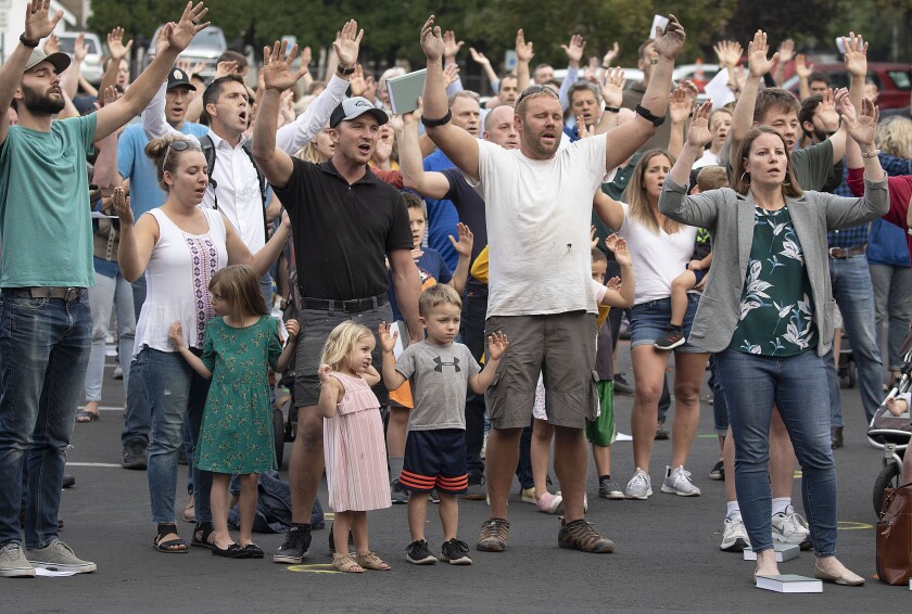 Christ Church members and guests in Moscow, Idaho, sing outside without masks, hands raised, to protest public health orders.