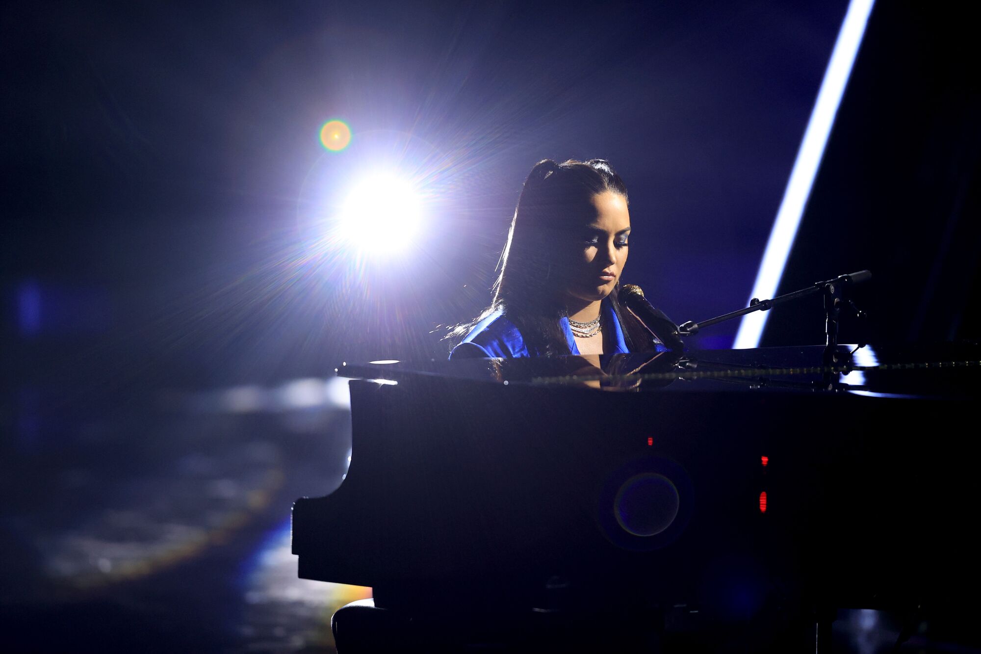 Demi Lovato sits at a grand piano as she performs at the 2020 Billboard Music Awards.
