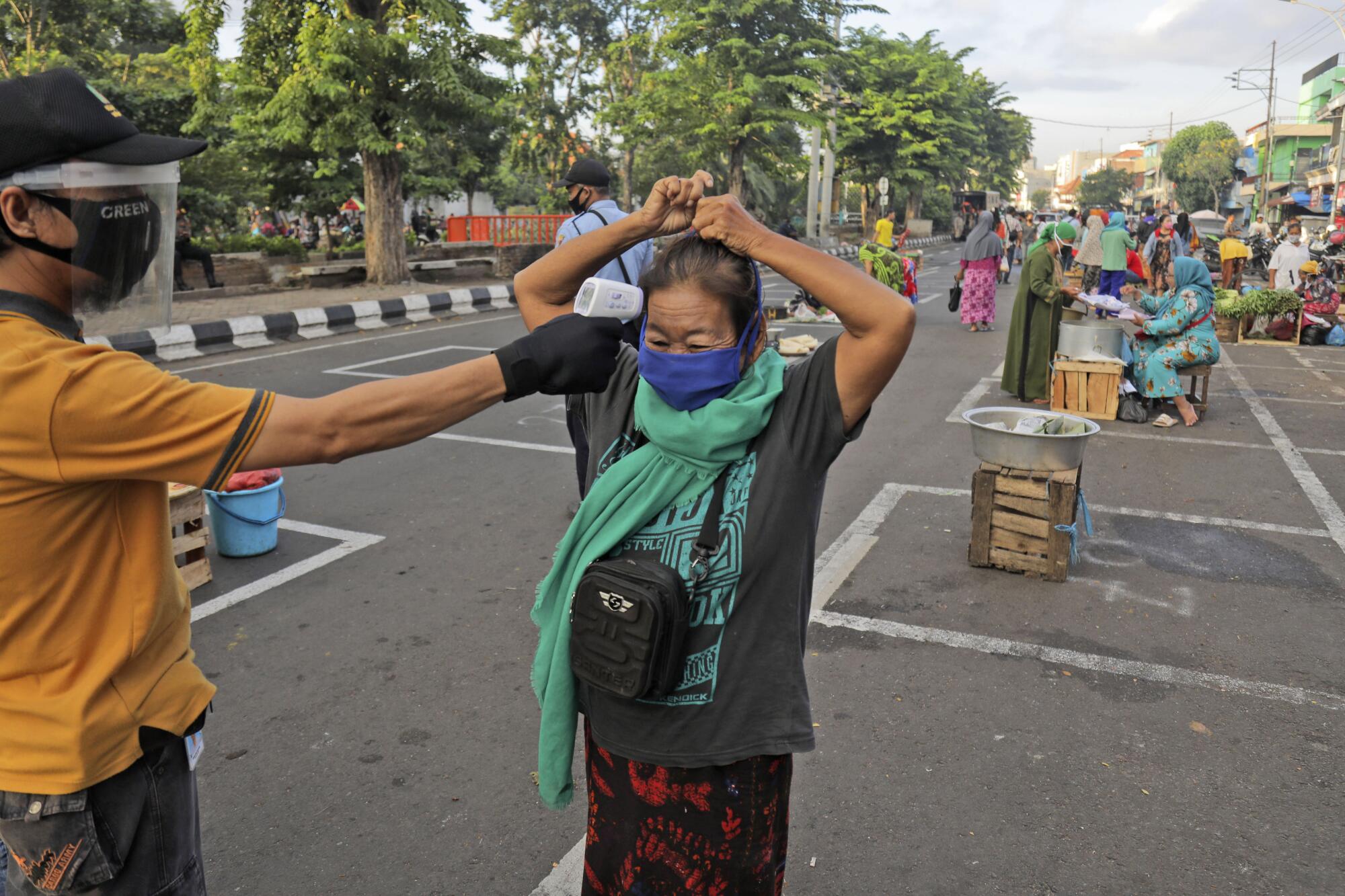 A city official takes the temperature of a vendor at a market in Surabaya, Indonesia.
