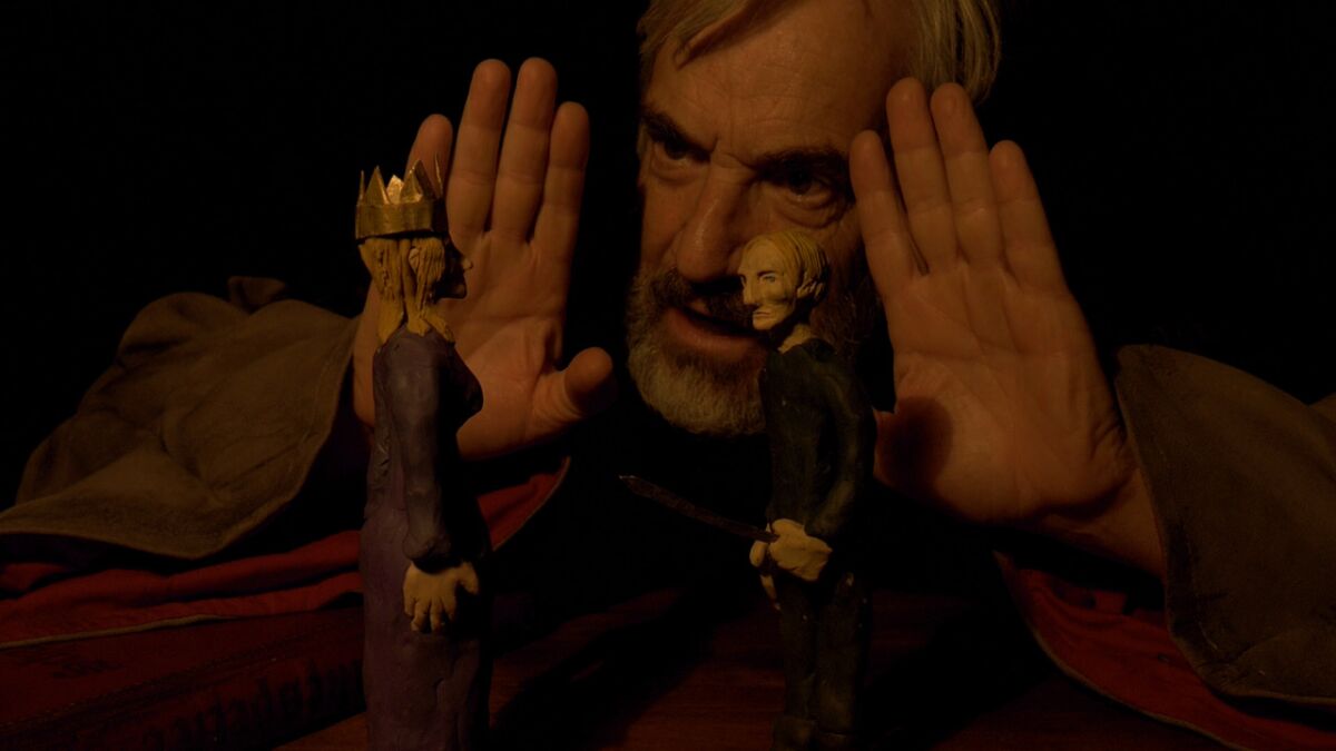 A still shows actor and director Francisco Reyes performing behind two plasticine puppets