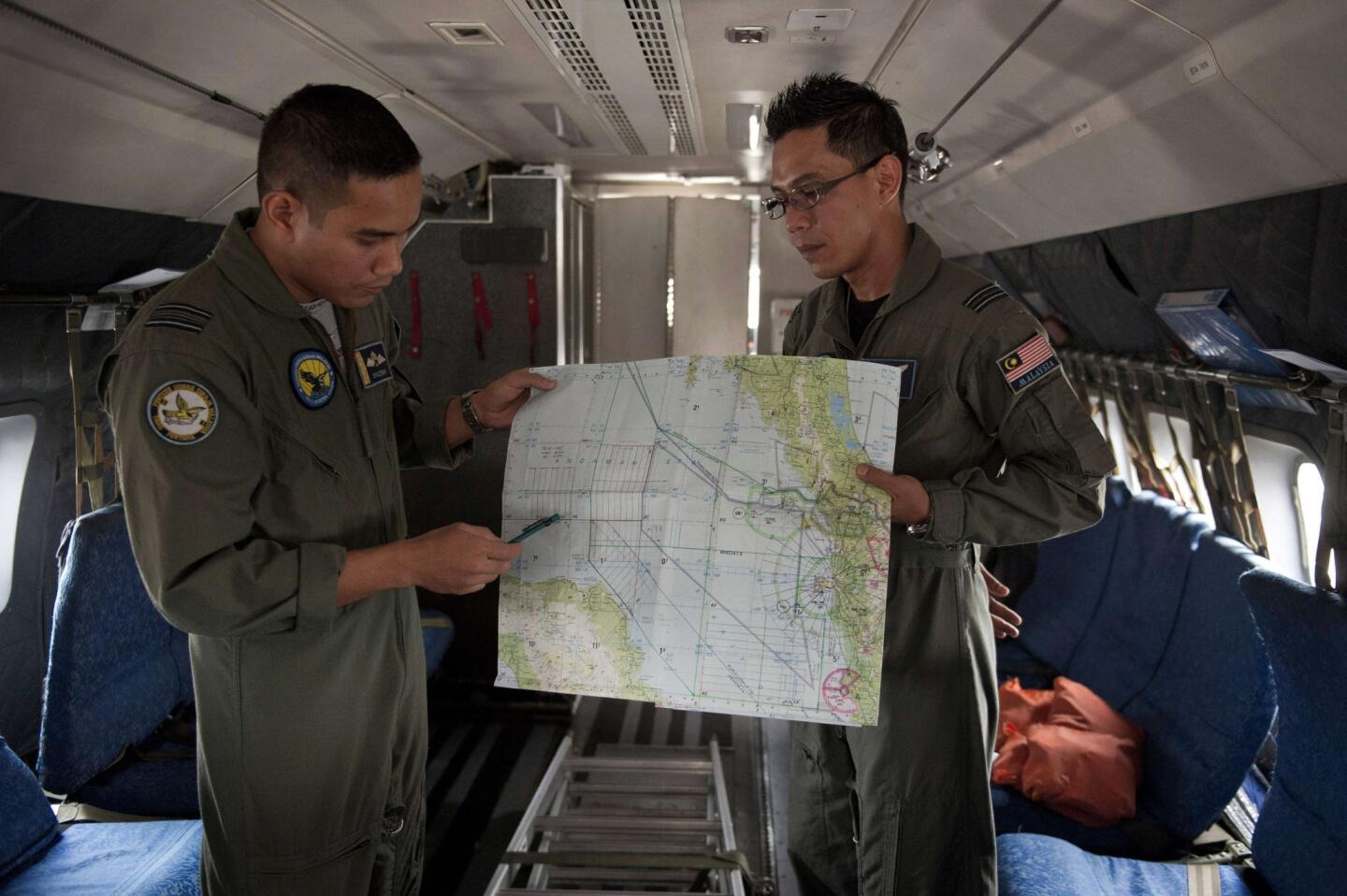 Royal Malaysian Air Force Navigator captain, Izam Fareq Hassan (R) and pilot major Ahmad Shazwan Mohammed (L) show locations on a map during a search and rescue operation to find the missing Malaysia Airlines flight MH370.