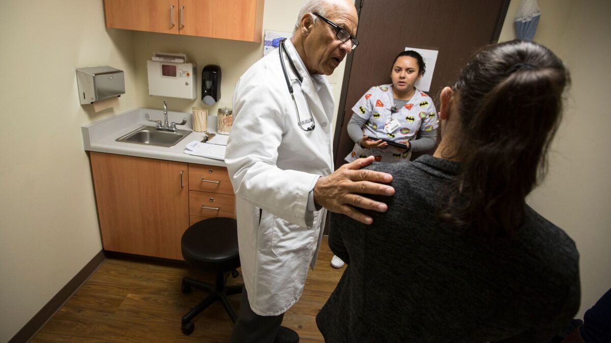 Dr. Karunyan Arulanantham, left, talks with a patient as medical assistant Marinela Castillo, center, is on hand to translate at the Antelope Valley Community Clinic in Lancaster.