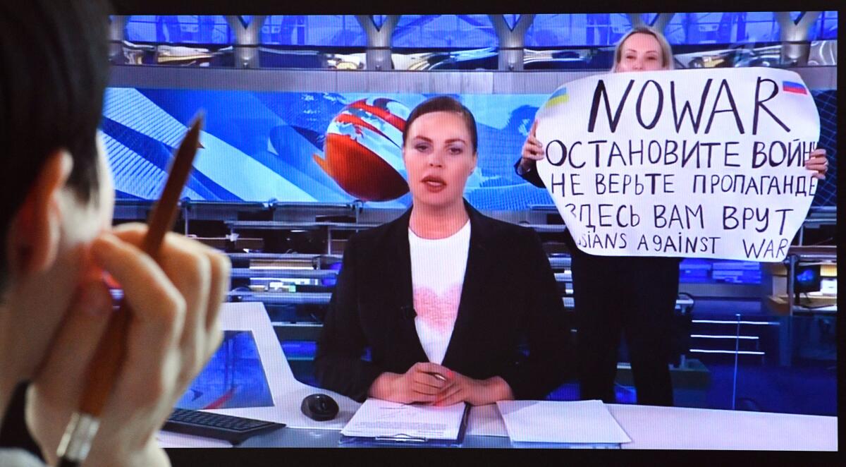 A woman looks at a computer screen watching a dissenting Russian Channel 1 employee