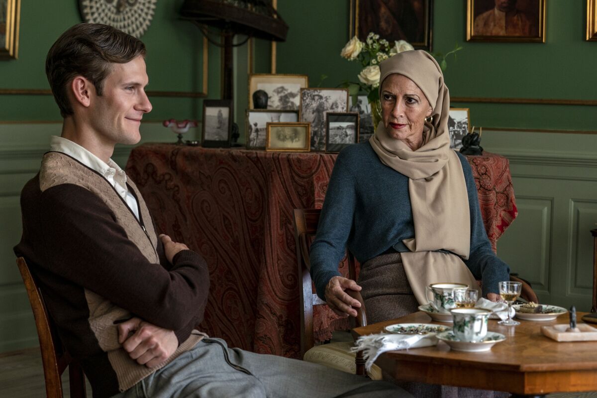 A man and a woman sit at a table set for tea.