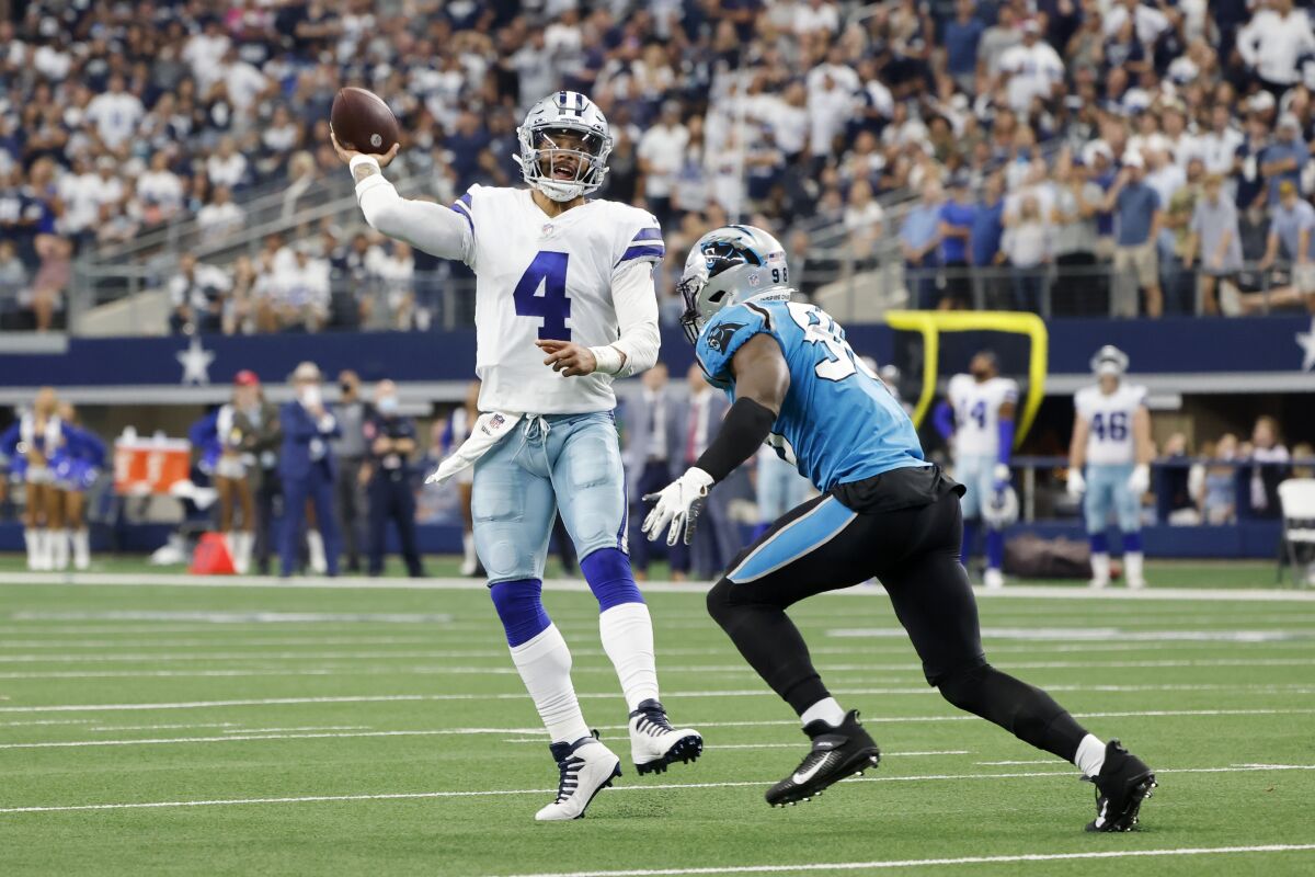 Dallas Cowboys quarterback Dak Prescott (4) throws a pass under pressure from Carolina Panthers defensive end Marquis Haynes in the second half of an NFL football game in Arlington, Texas, Sunday, Oct. 3, 2021. (AP Photo/Michael Ainsworth)