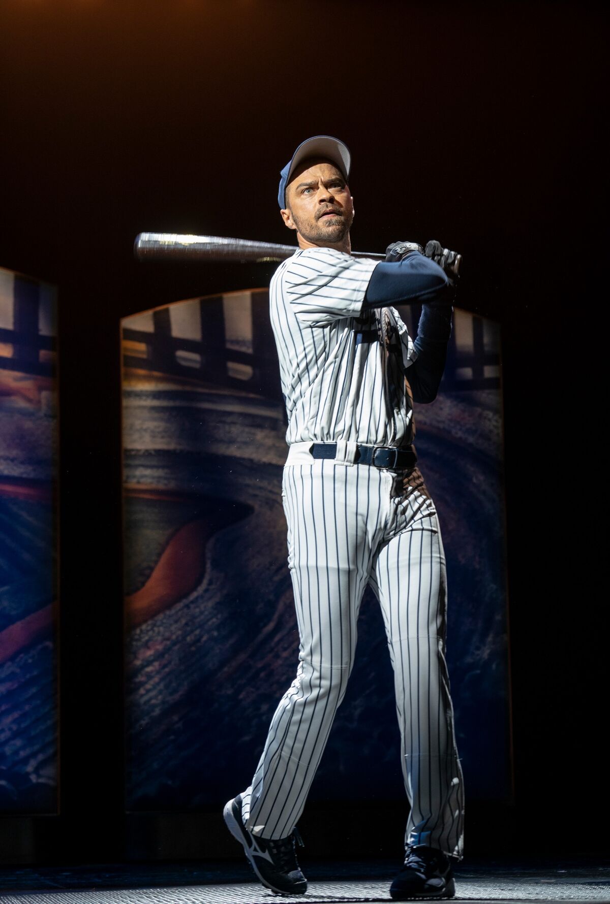 A man in a baseball uniform holds a bat aloft, ready to take a swing.