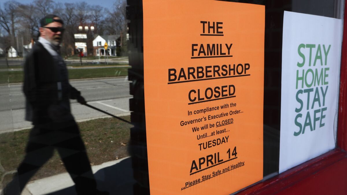 A pedestrian walks by The Family Barbershop, closed due to a Gov. Gretchen Whitmer executive order, in Grosse Pointe Woods, Mich., Thursday, April 2, 2020. The coronavirus COVID-19 outbreak has triggered a stunning collapse in the U.S. workforce with millions of people losing their jobs in the past two weeks and economists warn unemployment could reach levels not seen since the Depression, as the economic damage from the crisis piles up around the world. (AP Photo/Paul Sancya)