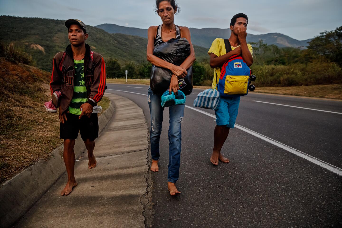 Johan Gonzalez, left, Doris Maralejo and Erik Corniel walk barefoot just south of Cúcuta, Colombia, in order to preserve their sandals for rougher and colder terrain ahead.