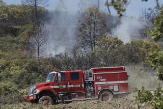 A Cal Fire truck drives down a hill after checking a hot spot near Lower Lake, Calif., Thursday, Aug. 13, 2015. Erratic winds fanned a wildfire burning through rugged hills in Northern California on Wednesday, pushing the flames across two counties and chasing people from their homes. (AP Photo/Jeff Chiu)