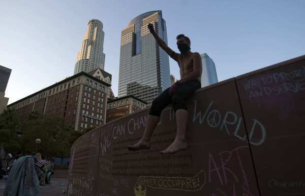 An Occupy L.A. member who called himself "Toxic" sits on a wall covered with chalk art at Pershing Square.