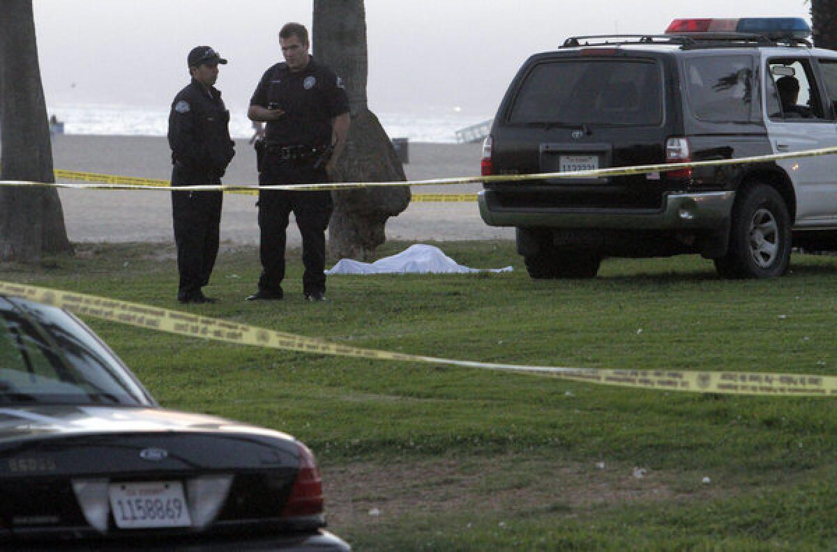LAPD officers wait for the coroner beside a man's body found on the Venice boardwalk near Breeze Avenue.