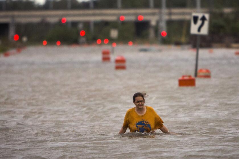 A woman walks along a flooded street after leaving her homeless encampment that was washed away by Hurricane Matthew in Savannah, Ga.