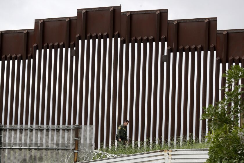 ARCHIVO -En esta foto del 18 de marzo del 2020, un agente de la Patrulla Fronteriza estadounidense camina junto al muro fronterizo que separa Tijuana, México, de San Diego, Estados Unidos. (AP Foto/Gregory Bull)