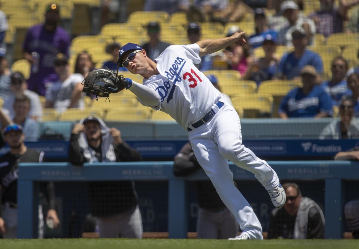 Joc Pederson lunges to catch a foul pop-up by Colorado's Brendan Rodgers.