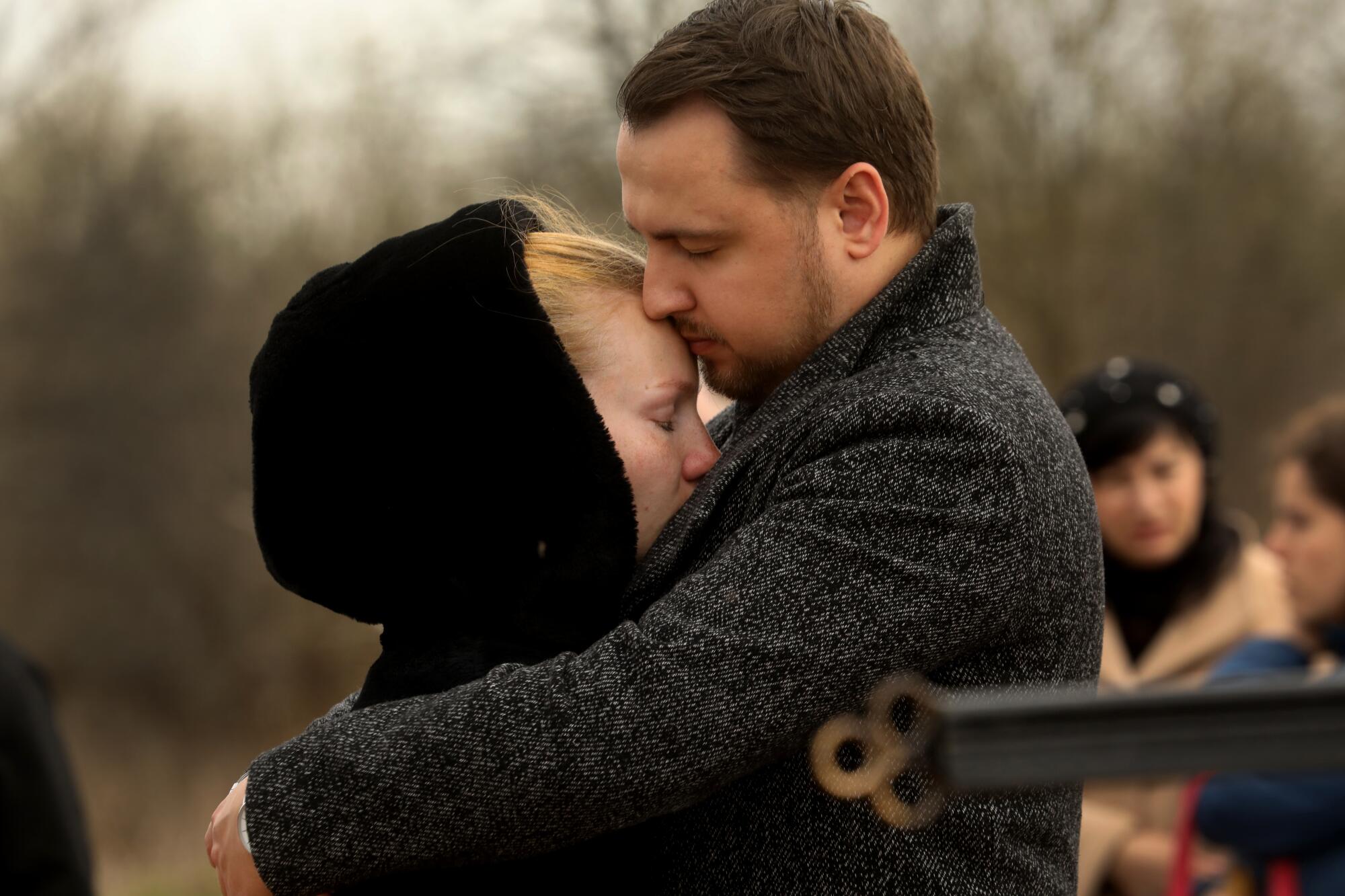 Veronkia Haidai, left, is consoled during the funeral for her relatives in Borodyanka.