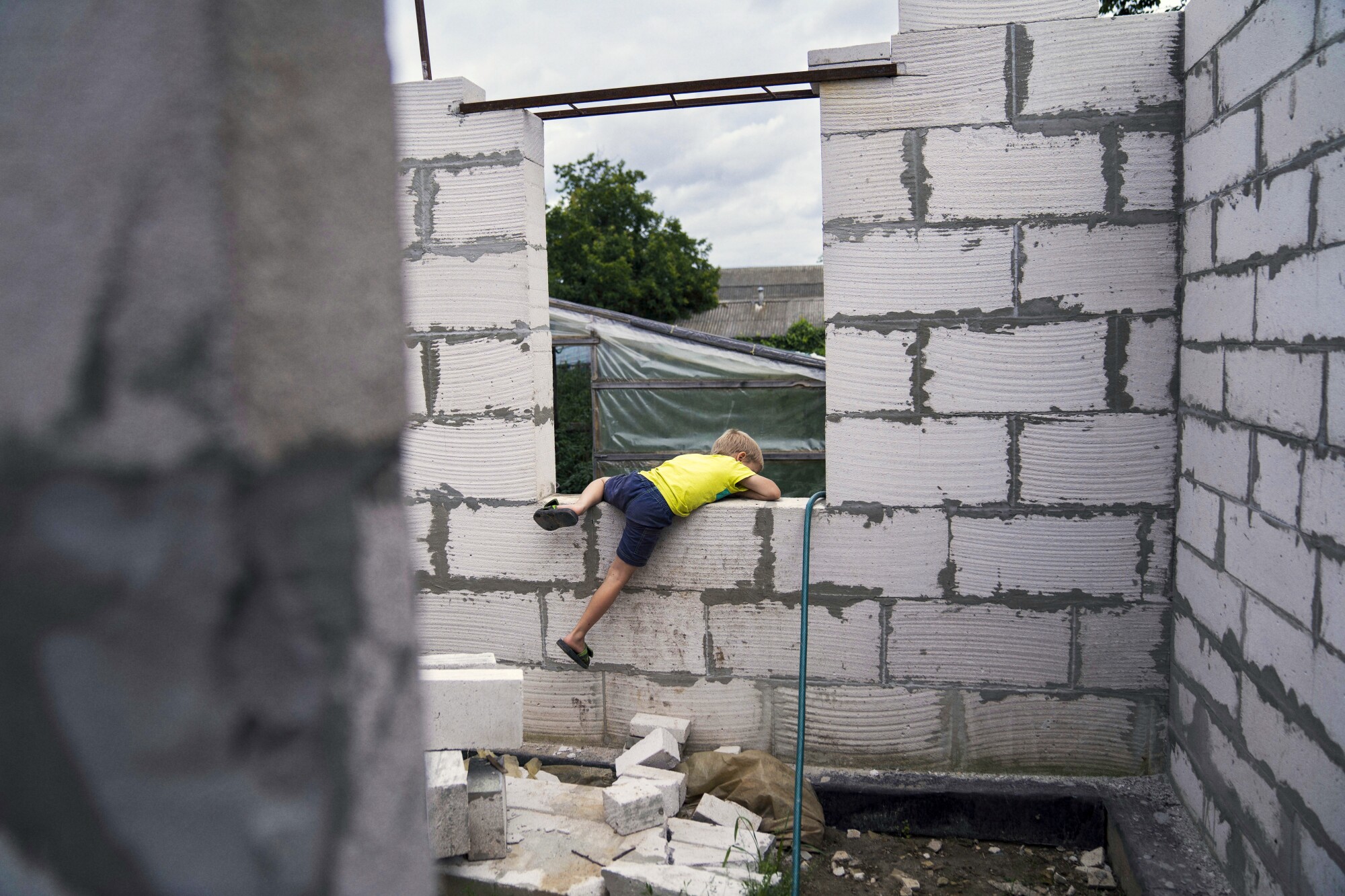 A boy climbs over a wall opening.