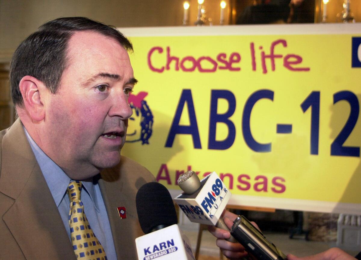 Arkansas Gov. Mike Huckabee speaks with reporters in front of a mock "Choose Life" license plate, after a bill signing in 2003.