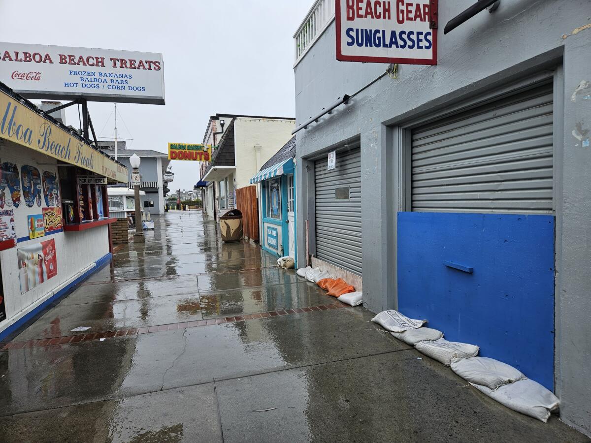 Sandbags line the front of some of the businesses in the Balboa Fun Zone on Sunday. Most were closed.