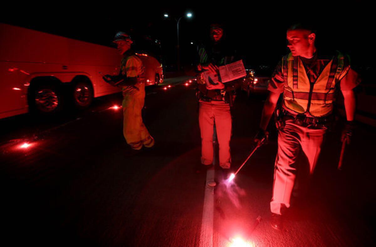 California Highway Patrolmen light flares as they investigate the scene of a limousine fire on the westbound side of the San Mateo-Hayward Bridge in Foster City, Calif.