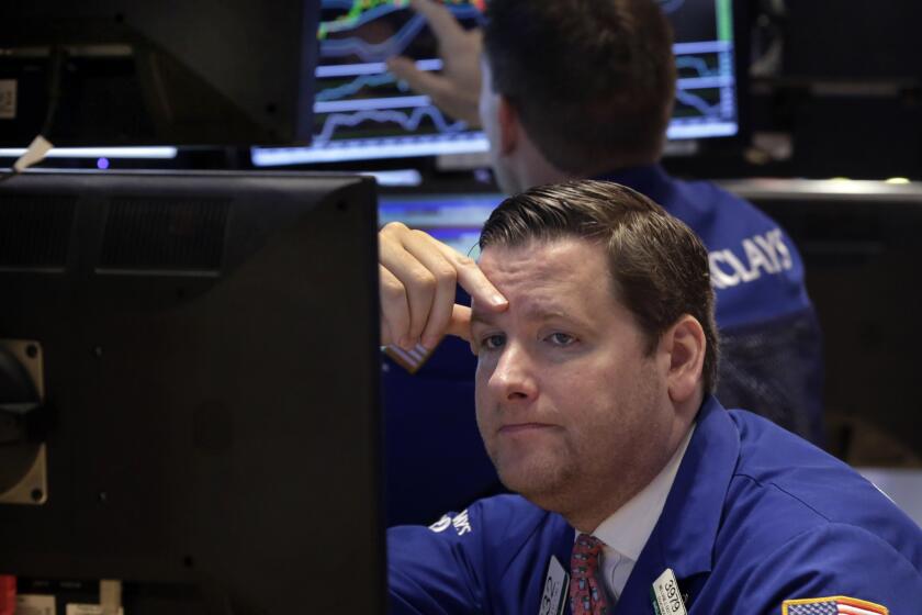 Trader Gregg Maloney works on the floor of the New York Stock Exchange, where stocks slid Monday on lower oil prices.