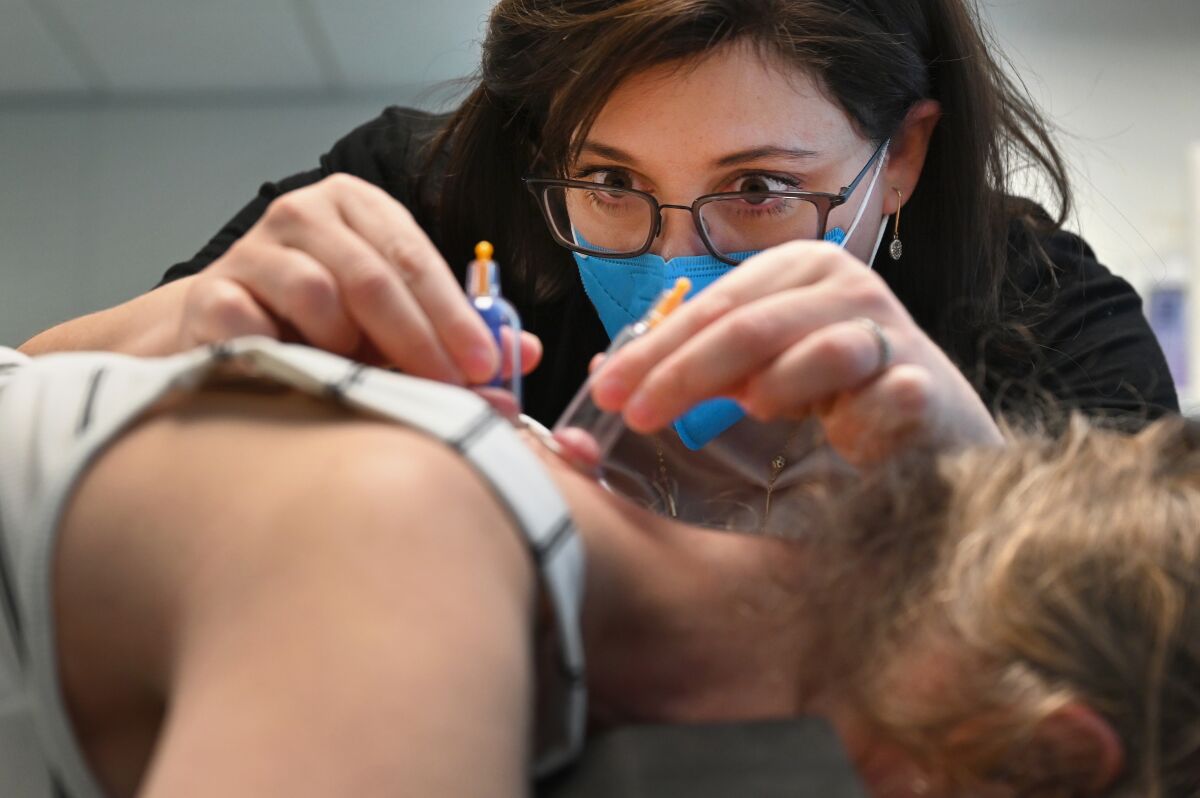 A doctor uses cupping therapy on a patient's upper back to help alleviate pain.