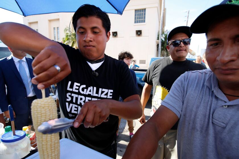 HOLLYWOOD, CA JULY 27, 2017: Benjamin Ramirez, left, with his father Alex Ramirez, right, serving food from their chart during a rally in Hollywood, CA July 27. March and Rally Los Angeles and Union del Barrio hold a rally in support of street vendor Benjamin Ramirez and street vendor legalization. Ramirez's cart was recently tipped over by a man saying Ramirez's street vending was illegal, contact says. (Francine Orr/ Los Angeles Times)