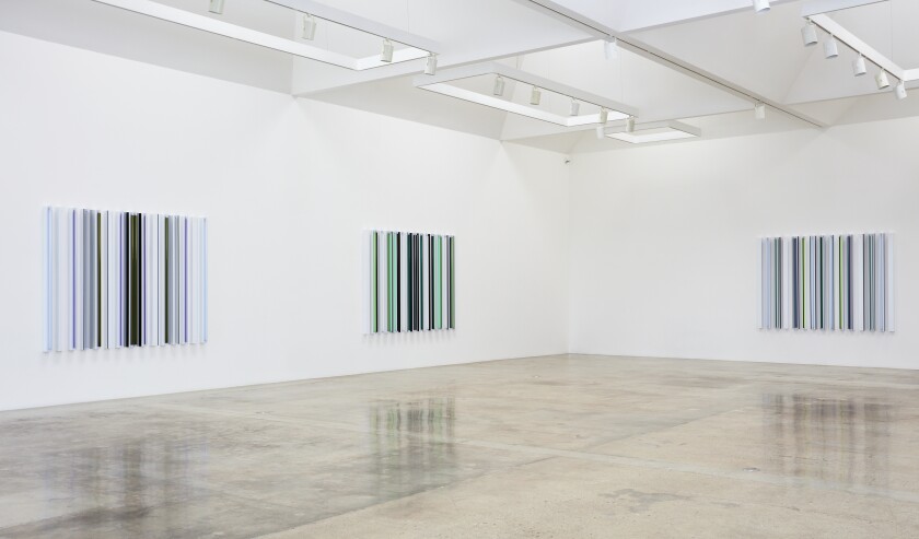 A series of three rectangular geometric pieces made from fluorescent tubes are visible in a white-walled gallery