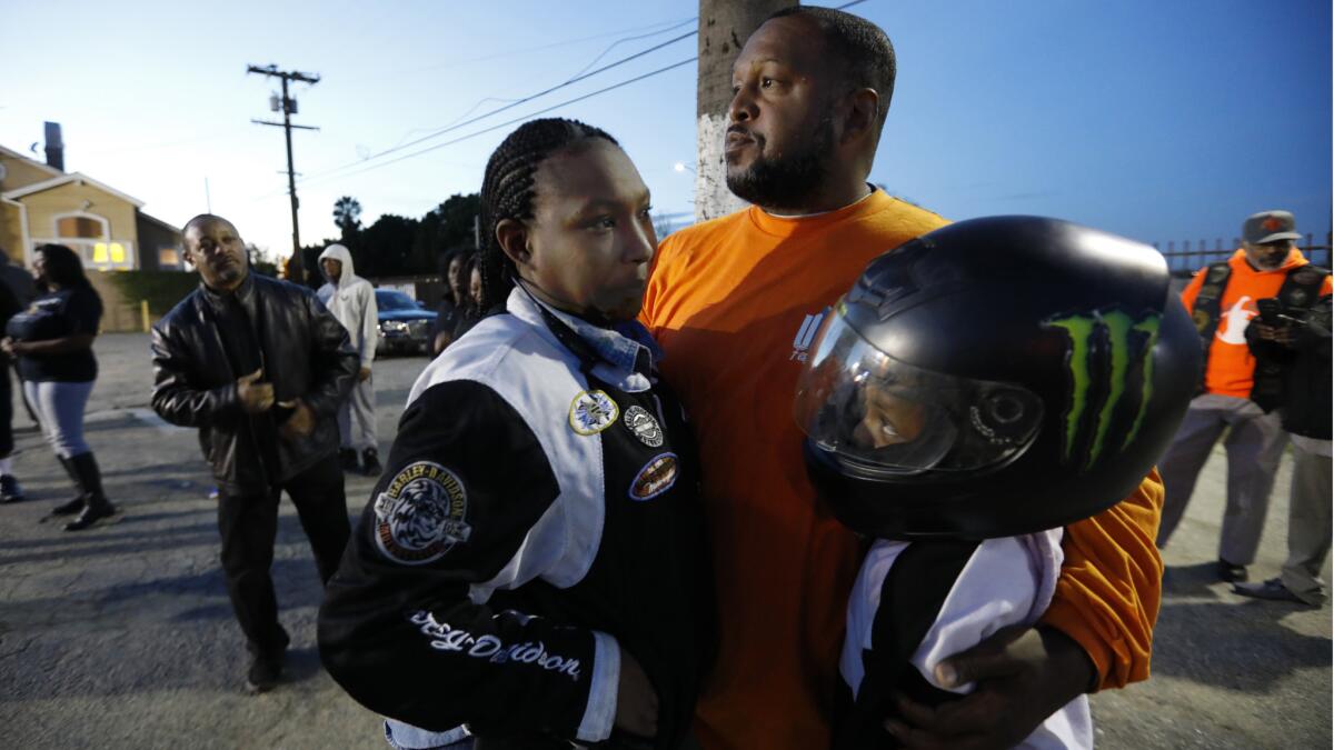 Eric Metoyer holds Kia Metoyer (L) and 12-year-old Emerie Metoyer as they attend a vigil near Nates Liquor Mart in Compton.