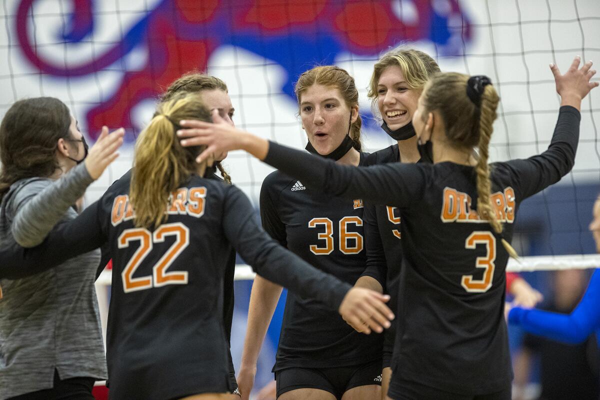 The Huntington Beach girls' volleyball team celebrates after scoring a point against Los Alamitos.