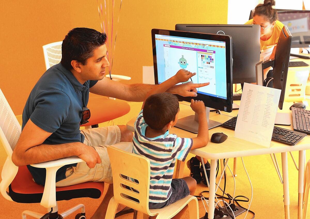 Jay Parikh works with his son Aakash at one of the character studio stations at the new Storymakery at the Irvine Spectrum.