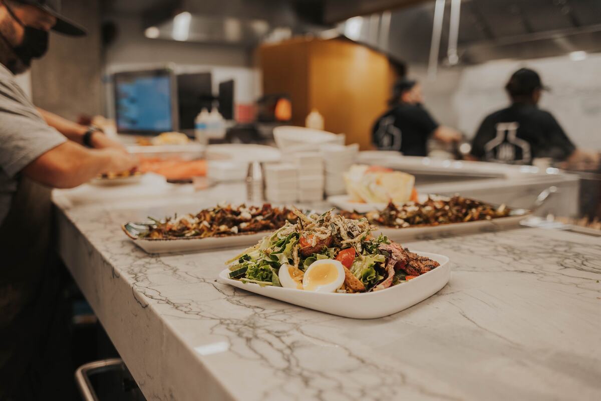 Salads and appetizers getting plated in The Lab Collaborative's large kitchen in Oceanside.