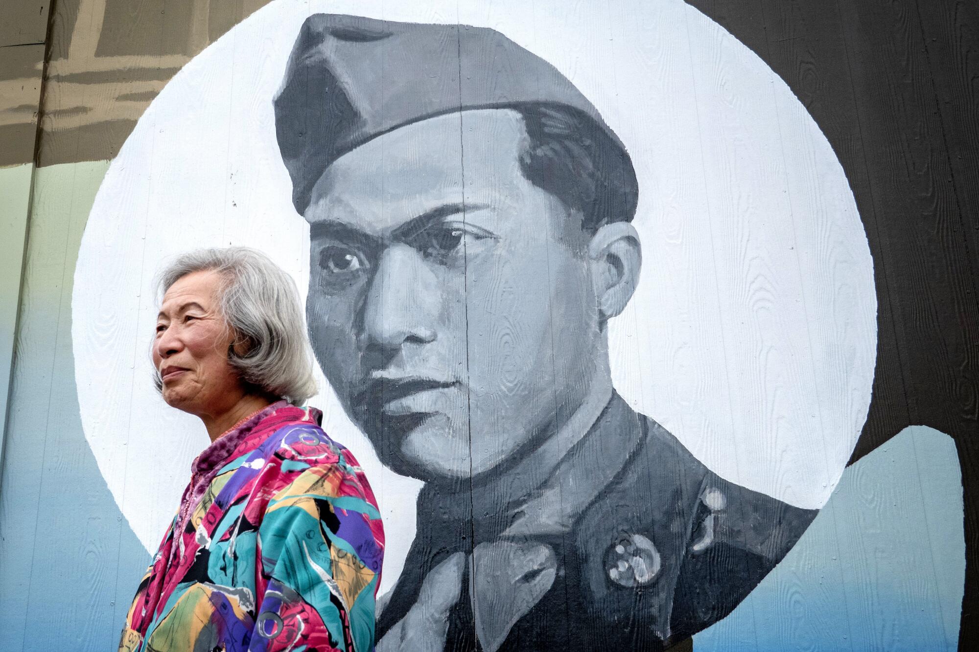 Mary Chin stands beside a mural in downtown Eureka, Calif., that depicts her late husband, Ben Chin.