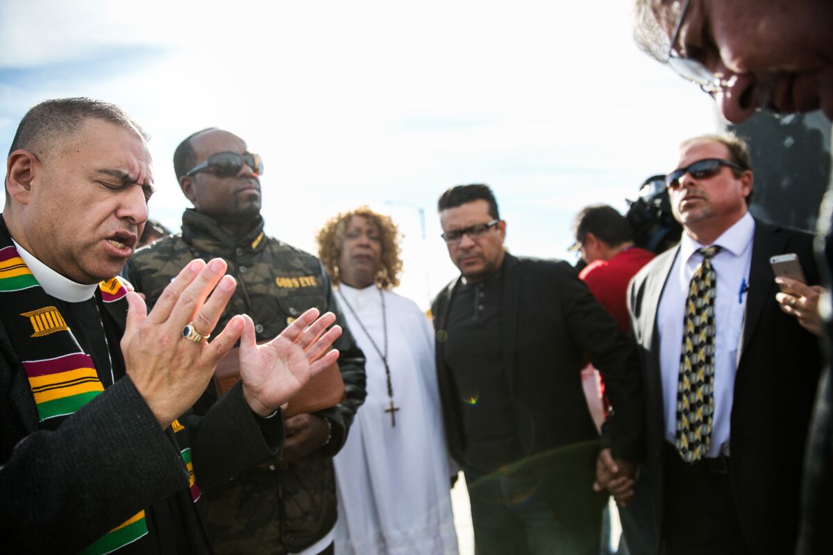 Pastor Juan Carlos Mendez, left, leads a coalition of church leaders as they bow their heads in prayers for the victims of the mass shooting in San Bernardino.