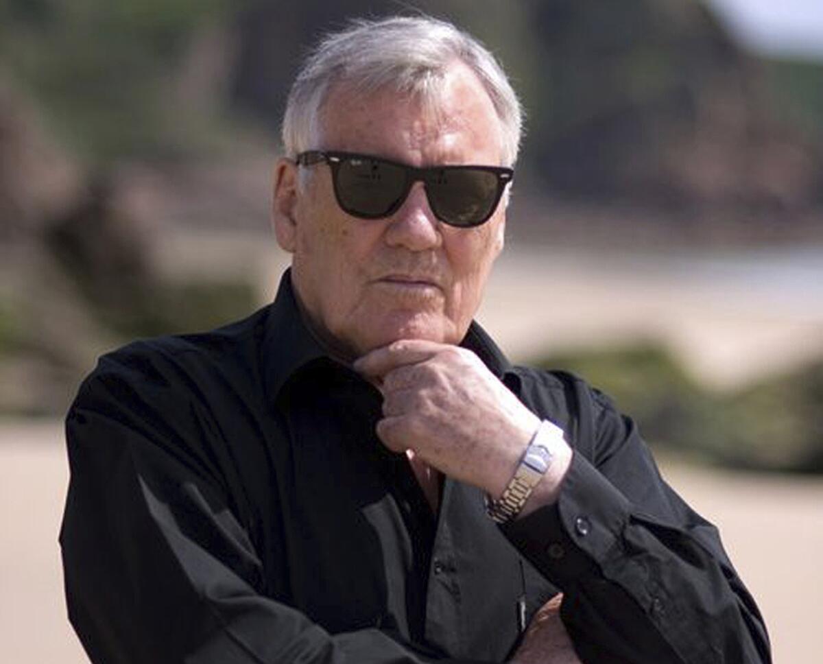 Jack Higgins wears sunglasses and strokes his chin in an author photo.