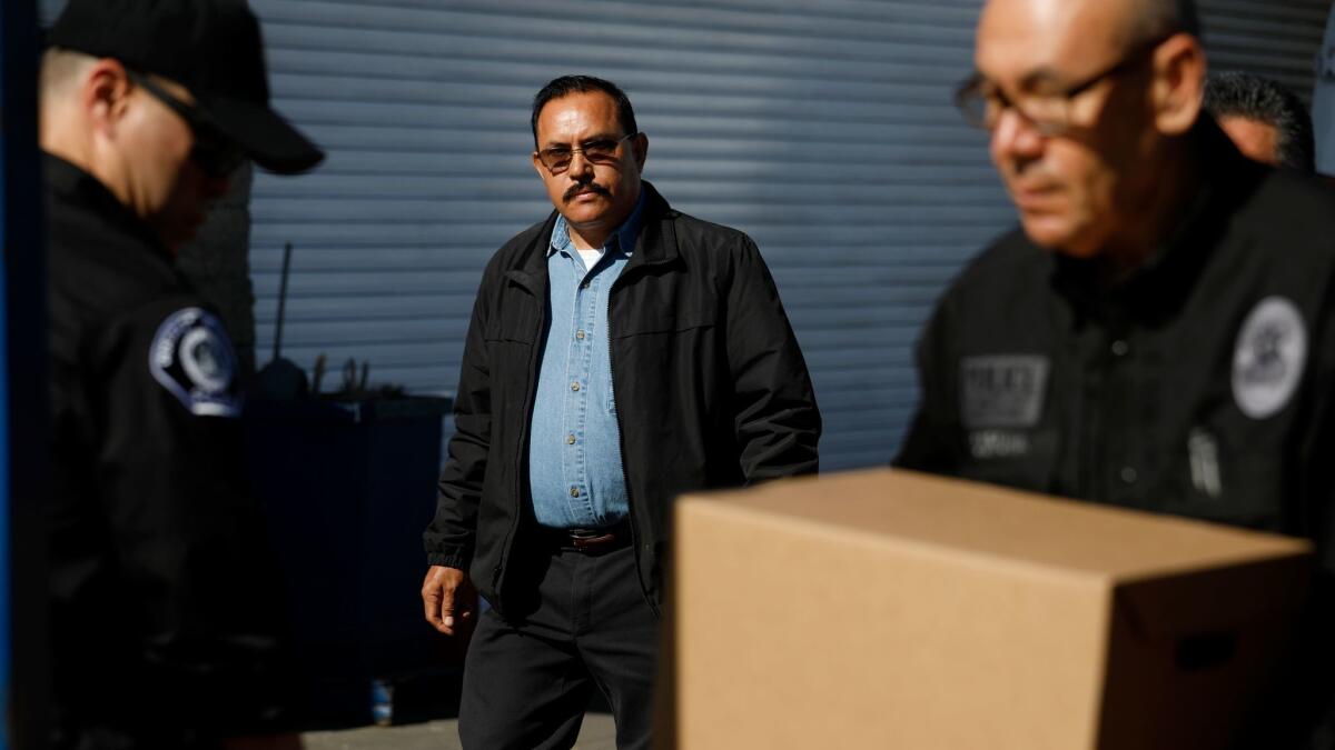 Maywood Mayor Ramon Medina keeps an eye on investigators Thursday as they remove boxes from Medina's R&M Auto Service.