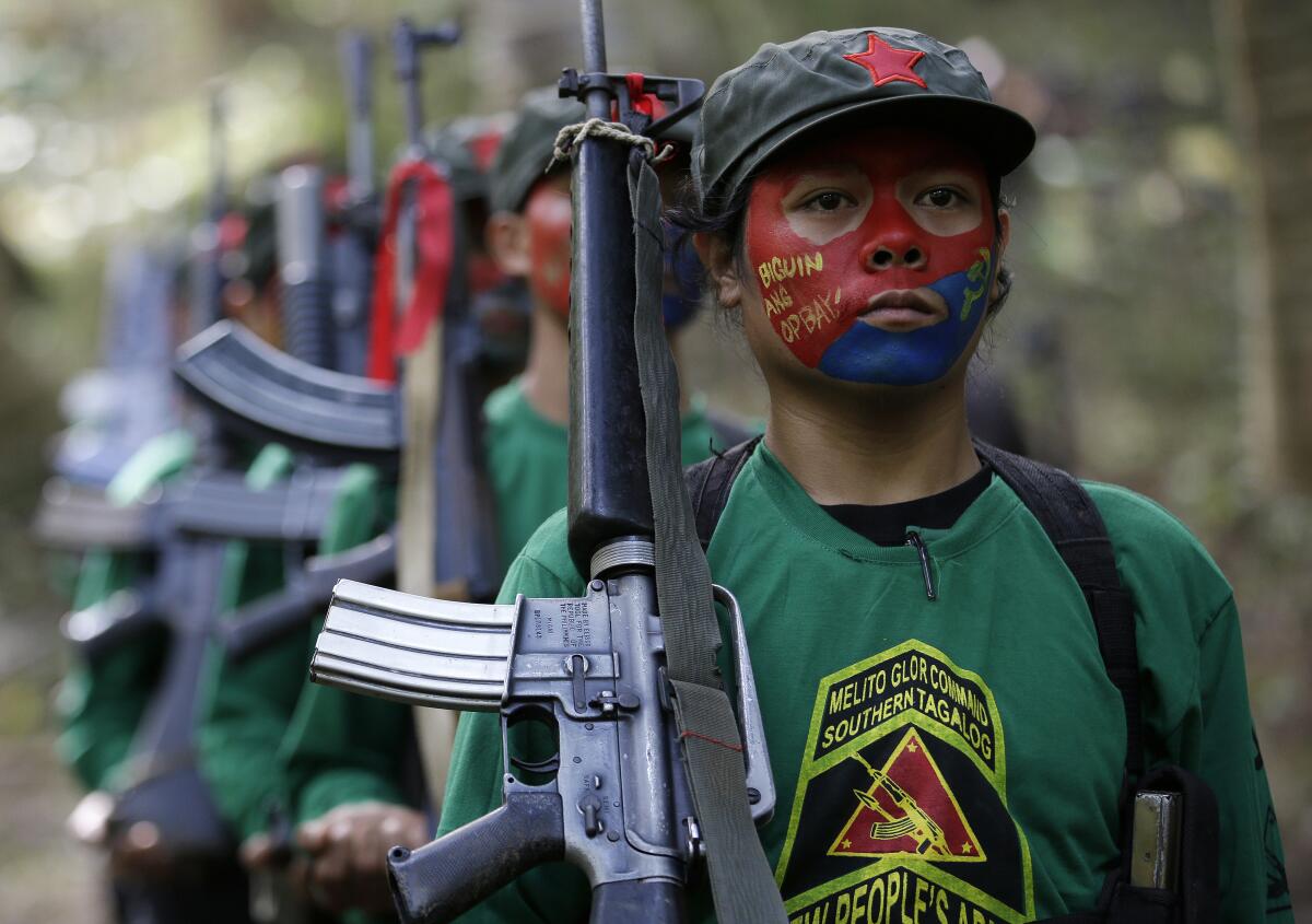 FILE - Members of the New People's Army communist rebels with face painted to conceal their identities, march with their firearms before a news conference held at their guerrilla encampment tucked in the harsh wilderness of the Sierra Madre mountains southeast of Manila, Philippines, Nov. 23, 2016. A land mine set by suspected New People's Army wounded seven soldiers in the central Philippines on Tuesday, July 5, 2022, in one of the insurgents’ first known attacks since President Ferdinand Marcos Jr. took office last week. (AP Photo/Aaron Favila)