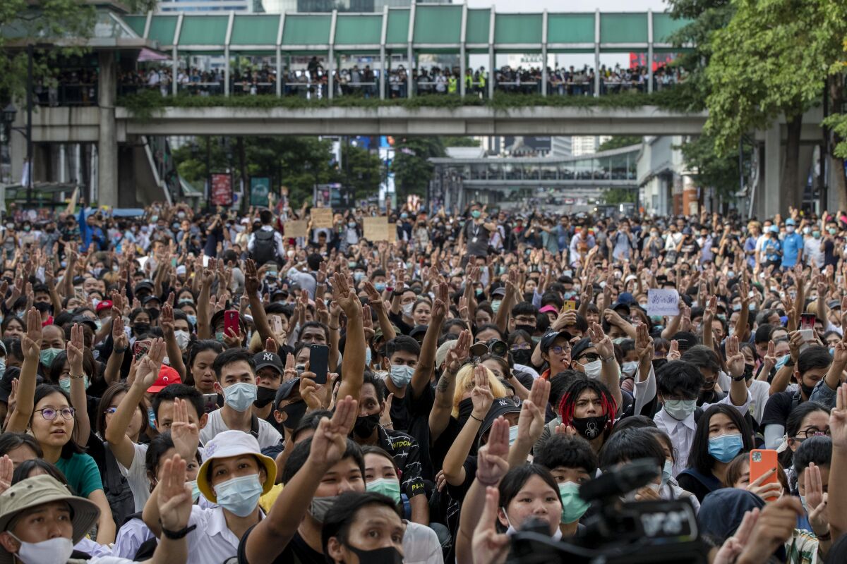 Pro-democracy protesters flash three-fingered salute during a protest as they occupied a main road at the central business district in Bangkok, Thailand, Thursday, Oct. 15, 2020. Thailand's government declared a strict new state of emergency for the capital on Thursday, a day after a student-led protest against the country's traditional establishment saw an extraordinary moment in which demonstrators heckled a royal motorcade. (AP Photo/Gemunu Amarasinghe)