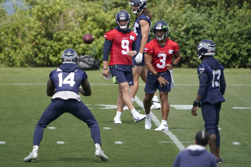 Seattle Seahawks quarterback Russell Wilson (3) passes to wide receiver DK Metcalf (14) during NFL football practice Tuesday, June 8, 2021, in Renton, Wash., as quarterback Danny Etling (9) and wide receiver Darvin Kidsy (23) look on. (AP Photo/Ted S. Warren)