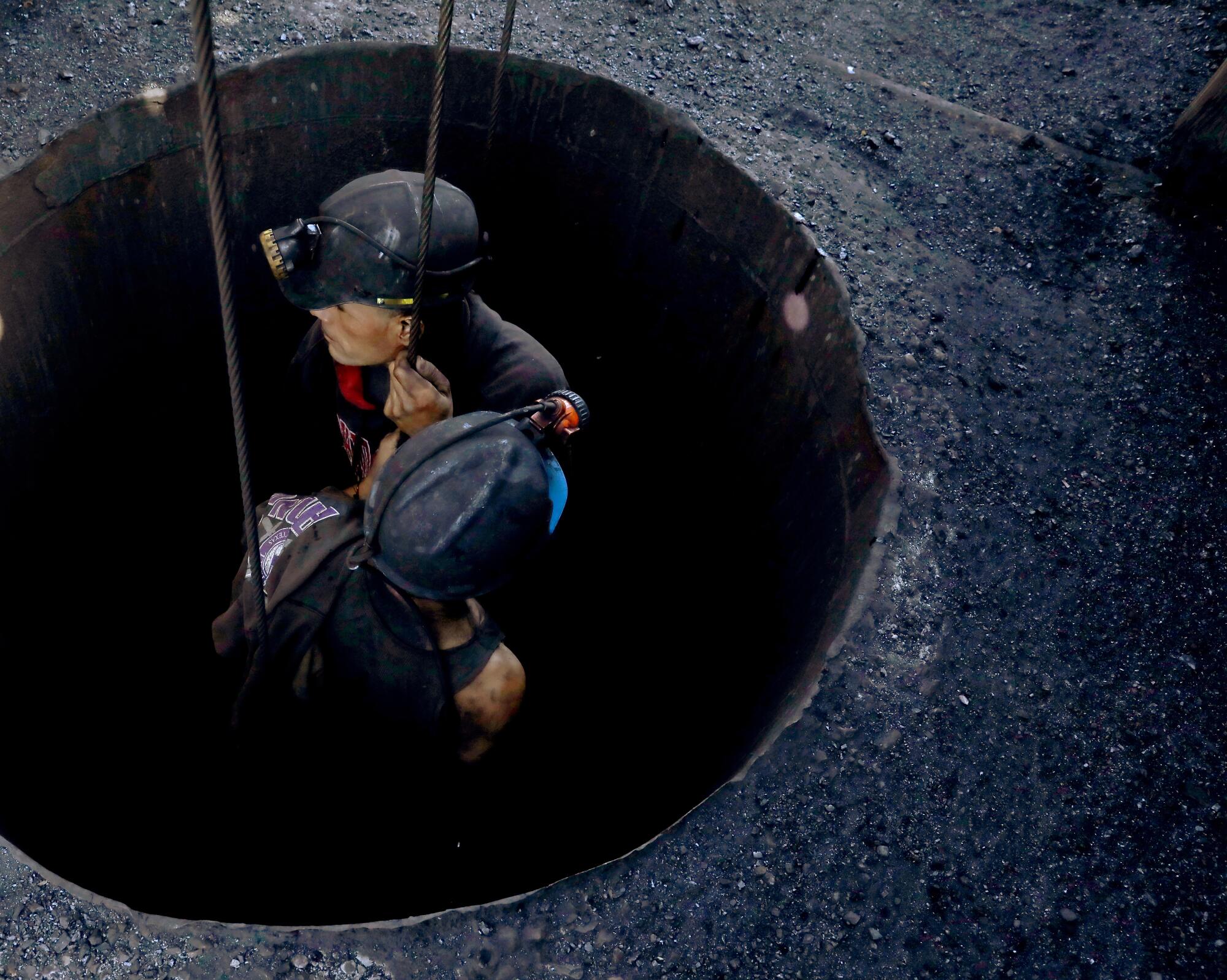 Two miners are pulled out of a mine with levers.