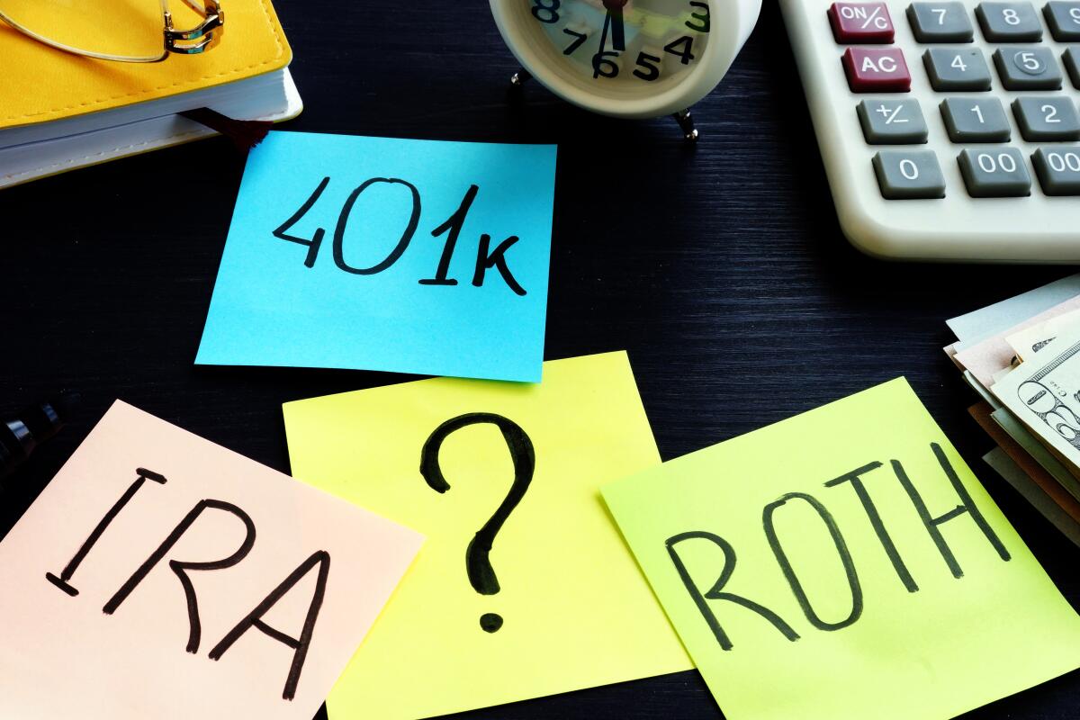 Post-it notes on a desk with the words 401k, Roth, IRA and a question mark.